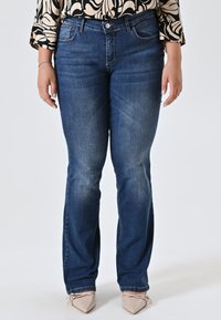 Jean en denim bleu foncé avec une coupe droite, un dégradé subtil, un design classique à cinq poches et une fermeture par bouton à l'avant.