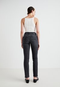 Black skinny jeans with back pockets, paired with a fitted white tank top. Smooth texture, medium-rise waist, and minimalistic design.