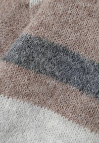 Megzto audinio, kuriame matomos švelnios smėlinės, pilkos ir grietinėlės juostelės; tekstūra yra pūkuota ir šilta, su išryškintu audimo raštu.