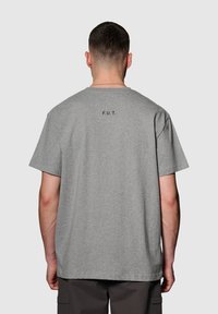 Grijze katoenen t-shirt met een ontspannen pasvorm, voorzien van korte mouwen en de tekst "F.U.T." in het zwart gedrukt op de bovenrug.