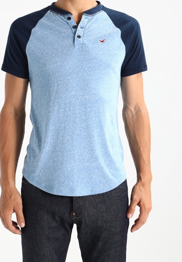 Helles blaues kurzärmliges Poloshirt mit marineblauem Kragen und Ärmeln, ausgestattet mit einer Dreiknopfleiste und einem kleinen Logo auf der linken Brust.