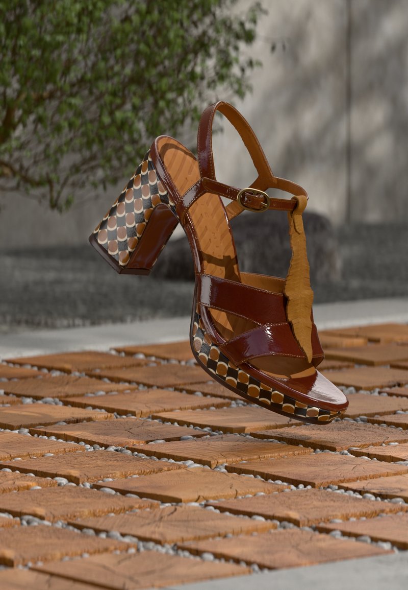 Καφέ δερμάτινα παπούτσια με τακούνι από πατέντα, με σχέδιο στο τετράγωνο τακούνι, λεπτά λουράκια και αγκράφα. Τοποθετημένα πάνω σε μια υφή επιφάνεια.