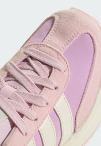 Rosa sportskor med en blandning av mocka och mesh. Rundad form med platta skosnören. Accentuerad med vita ränder och texturerade detaljer.