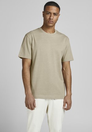 Beige T-Shirt mit kurzen Ärmeln aus Baumwolle. Verfügt über einen Rundhalsausschnitt und eine lässige Passform, kombiniert mit hellen Hosen.