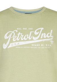 Lichtgroen katoenen t-shirt met witte vintage-stijl tekst voor "Petrol Ind" en een accentlijnontwerp bij de halslijn.