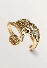 Anillo de tono dorado diseñado como un camaleón, con texturas intrincadas, una cola rizada y adornos de pequeños cristales transparentes.