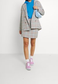 Plaid double-breasted blazer, blue hoodie, matching plaid skirt, and pink sneakers. Textured handbag in light blue adds detail.