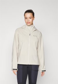Hellbeige wasserfeste Jacke mit Kapuze, Frontreißverschluss und weicher Textur. Merkmale sind ein Logo auf der linken Brust und schwarze Akzente an den Ärmeln.