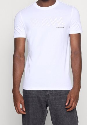 White short-sleeve t-shirt featuring a textured "RAW." logo in light grey. Made of cotton with a crew neck design. Worn with dark jeans.