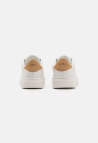 Sneakers bianchi in pelle con un accento in suede beige sul tallone, dettagli cuciti e una spessa suola in gomma bianca.