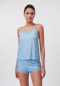 Ljusblå pyjamasset med spetsdetaljer. Linnen har små blommönster; shorts har en mjuk, slät textur med scallopade kanter.