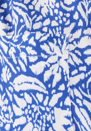 Tela con patrón floral abstracto en azul y blanco con un bolsillo rectangular visible cosido en la superficie.