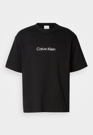 Μαύρο βαμβακερό T-shirt με κοντά μανίκια, που διαθέτει στο μπροστινό μέρος το λογότυπο "Calvin Klein" σε λευκό χρώμα και κλασική στρογγυλή λαιμόκοψη.