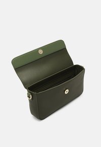 Liten mörkgrön läderclutch öppen, visar inre fack och guldtonad magnetknäppning.