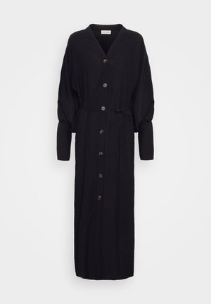Black long-sleeve dress made of textured fabric, featuring a V-neck, button front, and a tie waist. Includes gathered, puff sleeves and brown buttons.