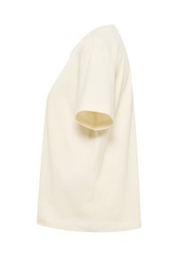 T-shirt à manches courtes, uni, de couleur blanc cassé, présenté de profil avec une coupe décontractée et un col rond, sur fond blanc.