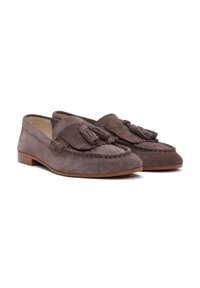 Mocassins en daim marron avec des accents de pampilles, talon plat, détails piqués, et une texture douce, conçus pour le confort et la polyvalence.