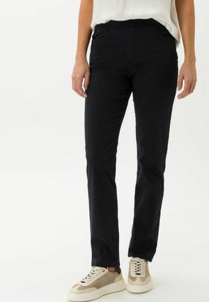 Schwarze gerade Hosen mit glatter Textur, ausgestattet mit Fronttaschen und einem dehnbaren Bund. Kombiniert mit beigen Turnschuhen.