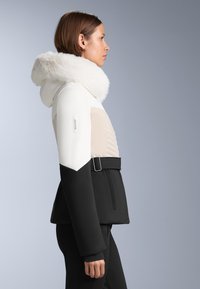 Ženska jakna s bijelim tijelom, crnim rukavima i kapuljačom obloženom krznom. Istaknuti detalji uključuju struk s remenom i kviltani dizajn.