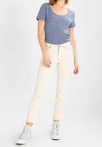 Light blue scoop-neck t-shirt, complemented by off-white straight-leg jeans with frayed hems; paired with grey high-top sneakers.
