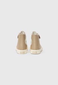 Augstākās beigu sporta kurpes, izgatavotas no gludas materiāla, ar baltu gumijas zoli un logo uzlīmi uz ārējā papēža.