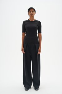 Melnas ribotas īsām piedurknēm blūze, kas savienota ar augstiem melniem plats kāju biksēm. Gluda tekstūra, pielāgota piegriezuma un minimālistisks dizains.