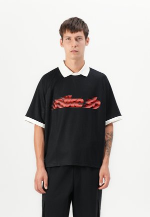 Schwarzes Polohemd mit kurzen Ärmeln, weißem Kragen und Bündchen, mit einem roten gestreiften Logo über der Brust. Glatter Stoff, lockerer Schnitt.
