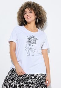 Camiseta de algodón blanca con un dibujo en línea negra de un pájaro con un lazo. Mangas enrolladas y escote redondo. La falda tiene un patrón de lazos.