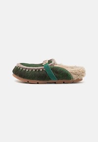 Green fur slip-on shoe with a cream inner lining, featuring a turquoise strap and stitched accents around the edges.