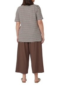 Gestreiftes T-Shirt in Braun- und Cremetönen, kombiniert mit lockeren, braunen, weiten Hosen. Weicher Stoff und lässige Passform.