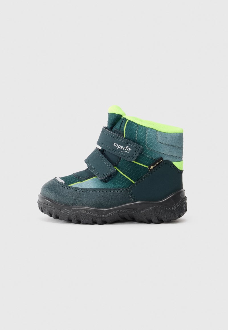 Botas de inverno para crianças em verde escuro e amarelo neon, com duas tiras de velcro, sola robusta e etiqueta Gore-Tex num fundo simples.