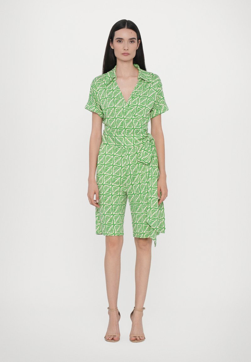 Combinaison à motifs verts avec motifs de feuilles, manches courtes et design croisé avec un lien à la taille, tombant au-dessus des genoux.