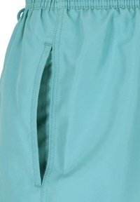 Turquoise stoffen short met een elastische tailleband en een zijzak, voorzien van nette stiksels en een zachte textuur.