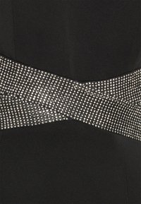 Černé šaty s širokým pásem třpytivých stříbrných rhinestones přes středovou část, vytvářející texturovaný, oku lahodící design.