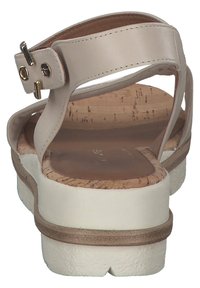 Sandale en cuir beige avec une semelle en liège, une semelle extérieure blanche et des accents en matériel doré sur la bride de cheville. Design à dos ouvert.