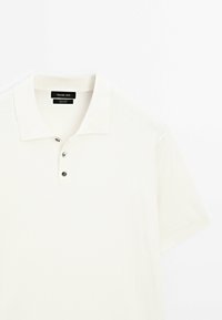 Polo blanc côtelé à manches courtes avec col et trois boutons, de la marque Massimo Dutti, en 100 % coton.