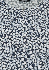 Dunkelblaue Bluse mit hellblauen und weißen kreisförmigen Mustern, mit einem runden Ausschnitt und einer kleinen Knopfdetailöffnung vorne.
