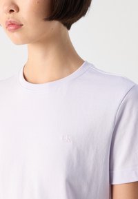 Lys lavendel bomull t-skjorte med rund hals og korte ermer, med en subtil brodert "ck"-logo på venstre bryst.