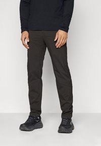 Mustad mustad väljas püksid, mis on vormitud disainiga, valmistatud kergest materjalist, omavad liigitatud põlvi ja elegantsset õmblust.