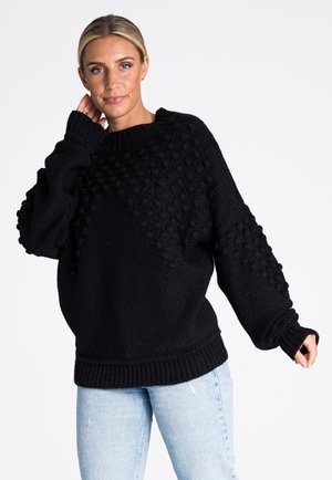 Czarny dziany sweter o oversize'owym kroju, ozdobiony teksturowanymi wzorami bobli na rękawach i górnej części, z prążkowanymi mankietami i dołem.