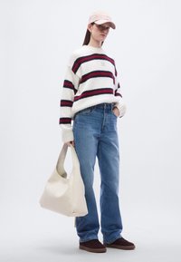 Χοντρή πουλόβερ πλεκτή με κόκκινες και ναυτικές ρίγες, μπλε τζιν, μπεζ τσάντα ώμου, ροζ καπέλο και σκούρα παπούτσια. Άνετες υφές και casual σχεδίαση.