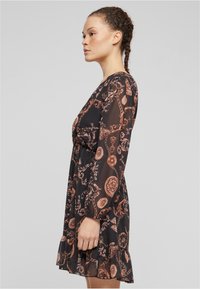 Rochie neagră transparentă cu mâneci lungi, cu modele florale și geometrice în nuanțe de cupru și crem, talie strânsă, tiv volanat.