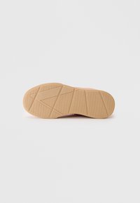 Shoe sole featuring a textured rubber surface with a pink side and a light tan, zigzag pattern for traction.