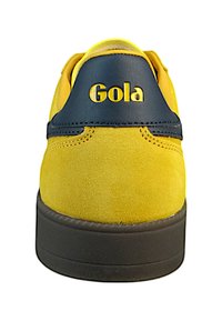 Gelbe Wildledersneaker mit dunkelblauen Lederakzenten, mit dem Markennamen "Gola" in Gelb auf der Ferse und einer dunklen Gummisohle.
