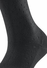 Chaussettes noires avec une surface texturée présentant de petits motifs à pois, fabriquées à partir d'un matériau extensible ; design ajusté pour le confort.