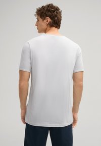 Lichtgrijze T-shirt met korte mouwen, voorzien van een ronde hals, zachte textuur en een licht gebogen zoom met minimale details.