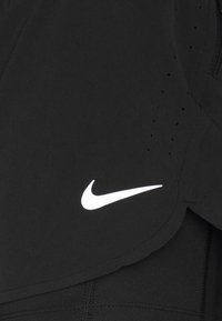 Shorts de sport noirs avec de petits trous de ventilation et un logo Nike swoosh blanc sur le côté avant inférieur.