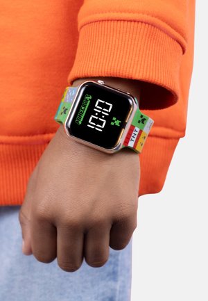 Orologio smartwatch a tema Minecraft, colorato, con un display digitale che mostra le 10:10. Il cinturino presenta grafiche e motivi vivaci, prevalentemente verdi e blu.