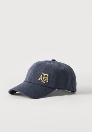 Casquette de baseball bleu marine avec une visière incurvée, avec le lettrage "ATA" brodé en jaune sur le panneau avant.