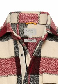 Rød, sort og creme-check overskjorte i uldblanding. Har en standard krave, lynlåslukning og fremtrædende mærkedetaljer indeni.